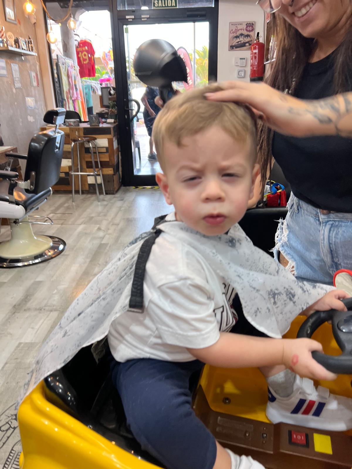Corte de niño en silla coche barbería
